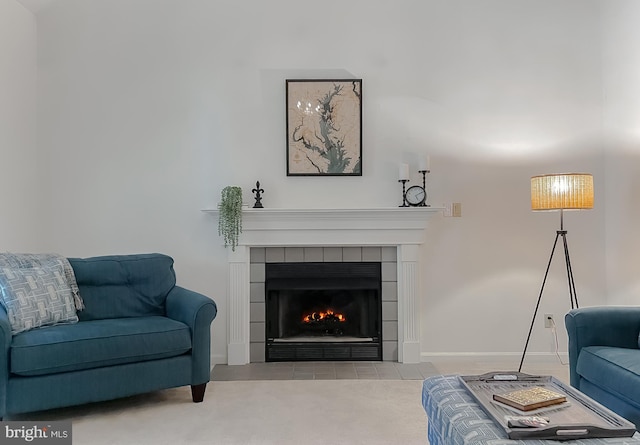 living room with a tiled fireplace, carpet, and baseboards