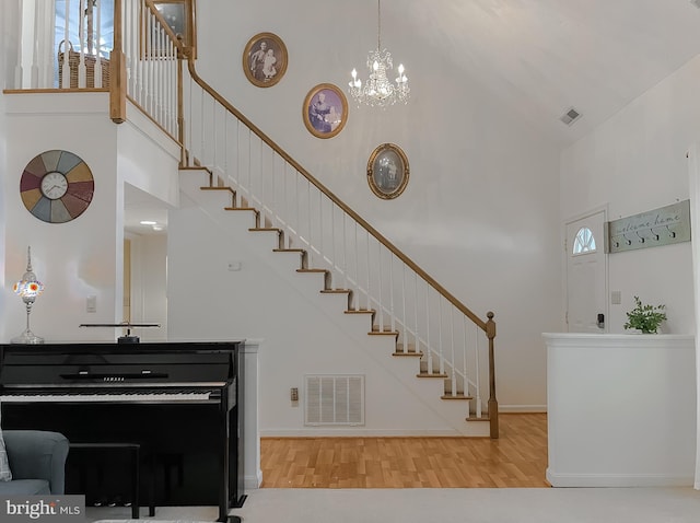 staircase featuring high vaulted ceiling, a wealth of natural light, wood finished floors, and visible vents