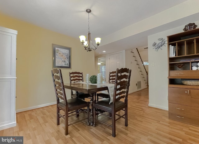 dining room featuring light wood-style floors, a chandelier, baseboards, visible vents, and stairway