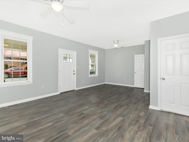 unfurnished living room featuring dark wood finished floors, visible vents, baseboards, and ceiling fan