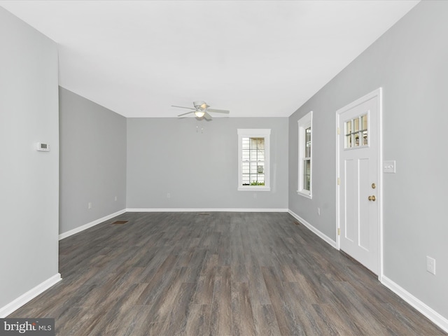 unfurnished living room featuring dark wood finished floors, baseboards, and ceiling fan