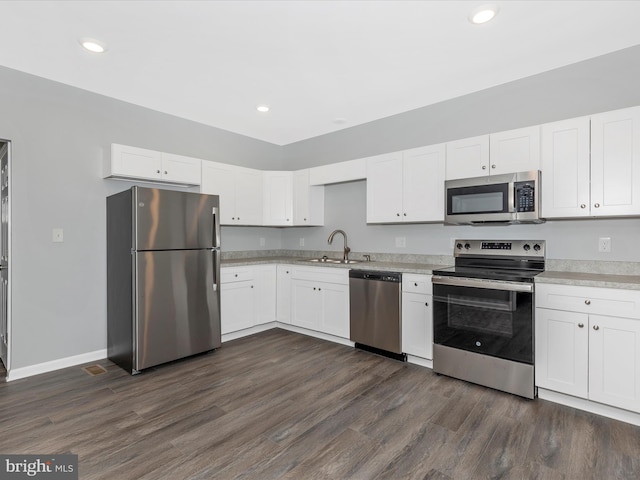 kitchen featuring white cabinets, a sink, dark wood finished floors, light countertops, and appliances with stainless steel finishes