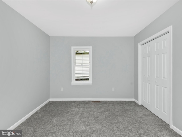 unfurnished bedroom featuring baseboards, carpet, and a closet
