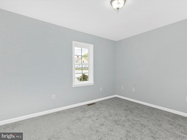 carpeted spare room with visible vents and baseboards