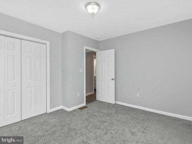 unfurnished bedroom featuring visible vents, baseboards, carpet floors, and a closet