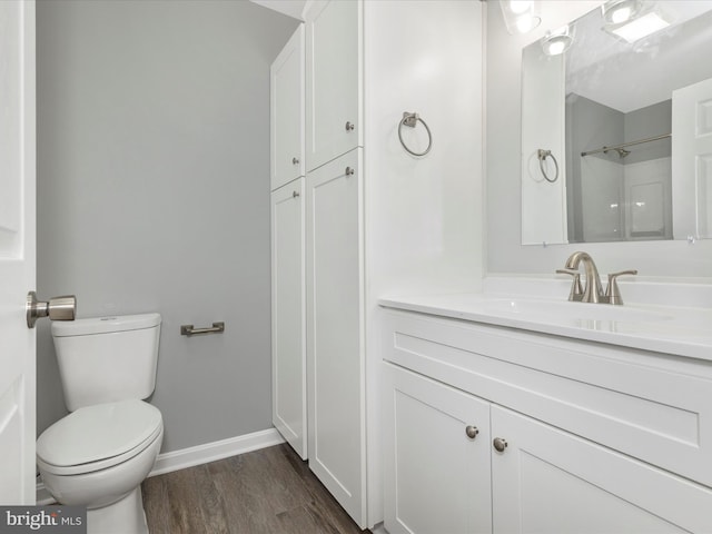 bathroom with wood finished floors, vanity, toilet, and baseboards
