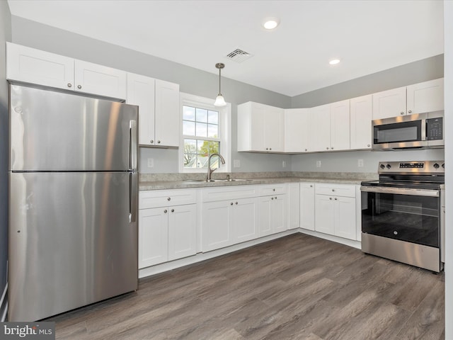 kitchen with a sink, recessed lighting, white cabinetry, dark wood-type flooring, and appliances with stainless steel finishes
