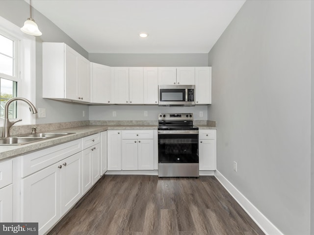 kitchen featuring white cabinets, light countertops, a sink, appliances with stainless steel finishes, and dark wood-style flooring
