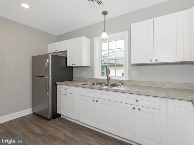 kitchen with white cabinets, a sink, visible vents, and freestanding refrigerator