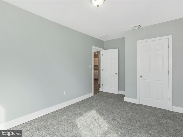unfurnished bedroom with dark carpet, visible vents, and baseboards