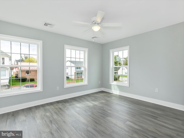 unfurnished room with visible vents, baseboards, dark wood-type flooring, and ceiling fan