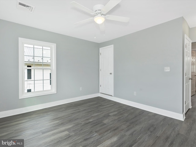 unfurnished room with ceiling fan, baseboards, dark wood-style flooring, and visible vents