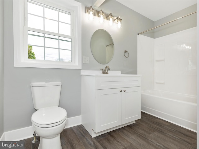 bathroom with toilet, wood finished floors, vanity, washtub / shower combination, and baseboards