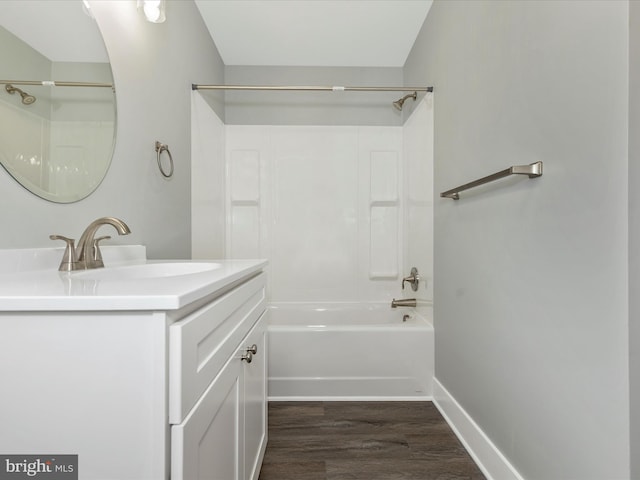 full bathroom with baseboards, wood finished floors, vanity, and shower / washtub combination