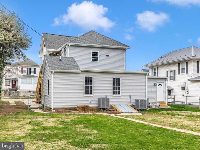 back of house featuring central AC unit, a shingled roof, fence, a yard, and entry steps