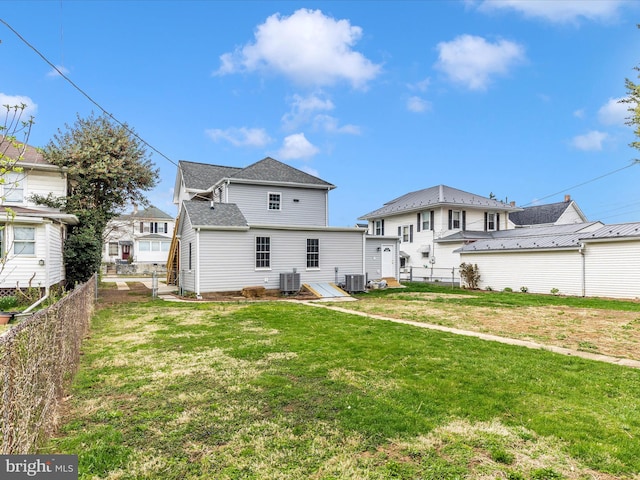 back of property featuring central air condition unit, a lawn, and fence