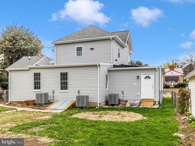 rear view of property featuring cooling unit, a yard, and fence