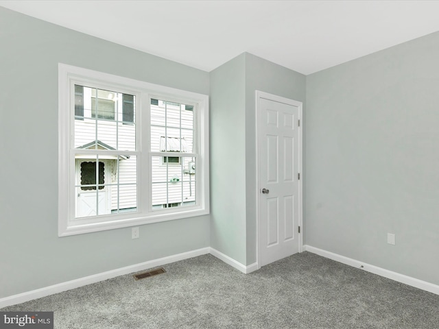 unfurnished room featuring baseboards, visible vents, and carpet