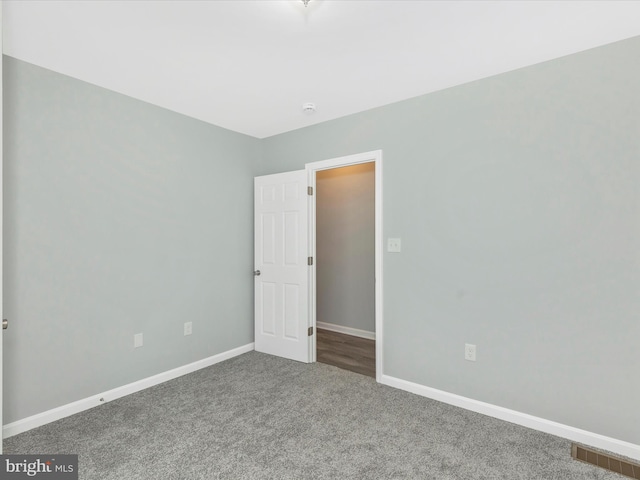 carpeted empty room featuring baseboards and visible vents