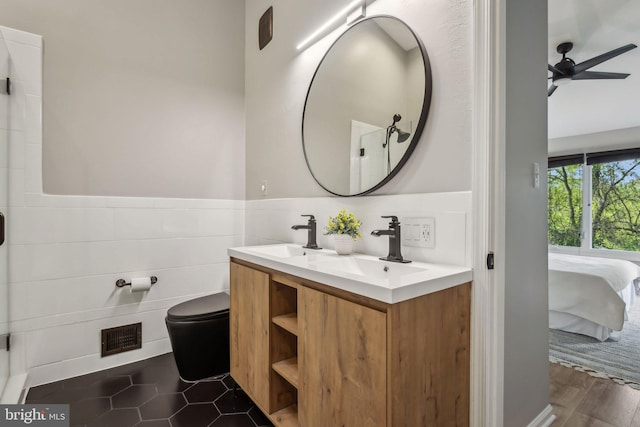 1070 Trevino Ln, Herndon, VA 20170 - ensuite bathroom featuring visible vents, a ceiling fan, double vanity, a wainscoted wall, and a sink