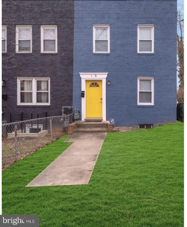 view of front of house with fence, brick siding, and a front yard