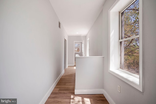 hall with baseboards, wood finished floors, and visible vents
