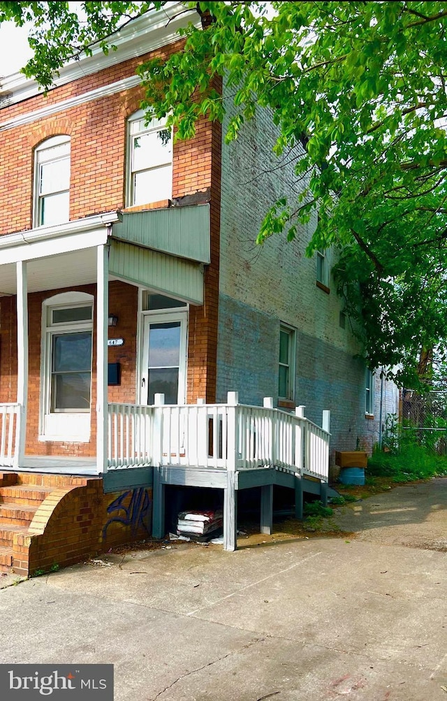 view of property exterior featuring covered porch and brick siding