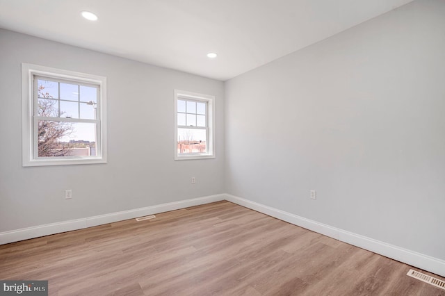 spare room with baseboards, visible vents, a wealth of natural light, and light wood finished floors