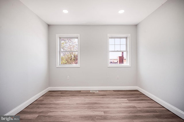 spare room featuring recessed lighting, baseboards, and wood finished floors