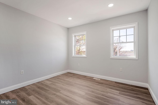 spare room with baseboards, recessed lighting, wood finished floors, and visible vents