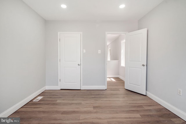 unfurnished bedroom with baseboards, recessed lighting, wood finished floors, and visible vents