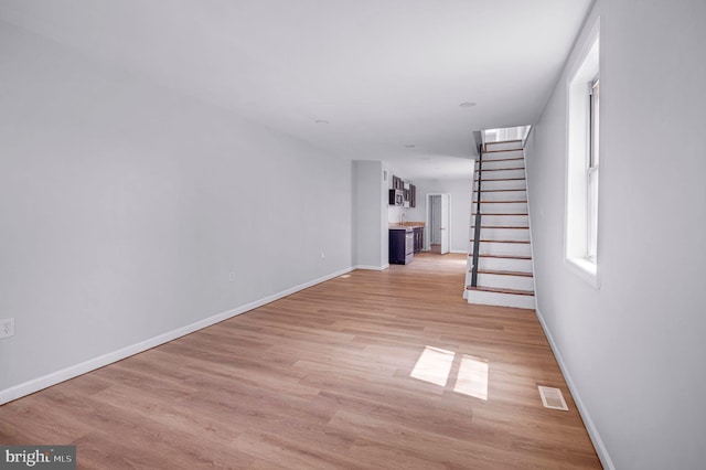 interior space featuring baseboards, light wood-style flooring, stairs, and visible vents