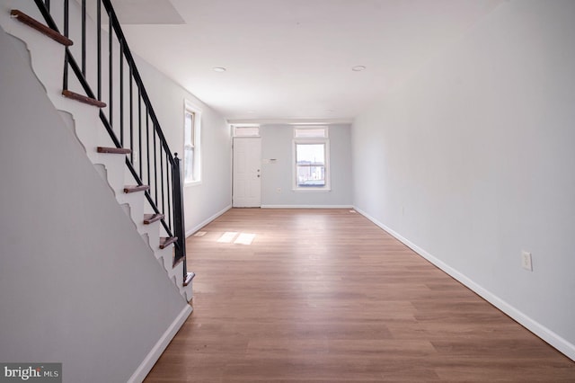 entrance foyer with baseboards, wood finished floors, and stairway