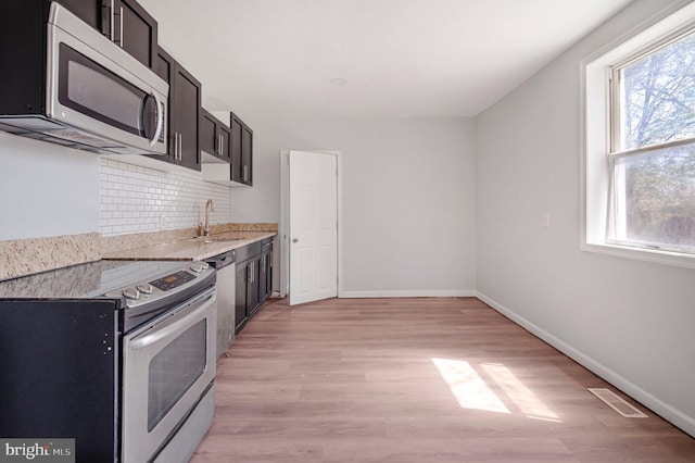 647 S Pulaski St, Baltimore, MD 21223 - kitchen featuring visible vents, baseboards, light wood finished floors, appliances with stainless steel finishes, and backsplash
