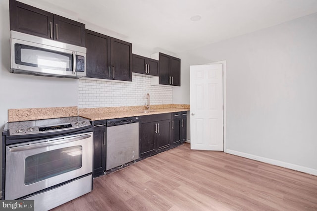kitchen featuring dark brown cabinets, light wood-type flooring, tasteful backsplash, a sink, and stainless steel appliances