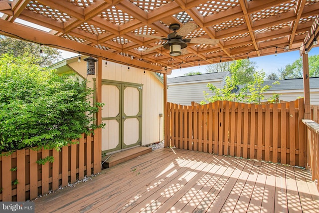 wooden terrace featuring an outbuilding, a pergola, a ceiling fan, and a storage unit