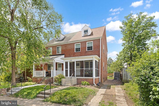 view of front of home with brick siding and a sunroom