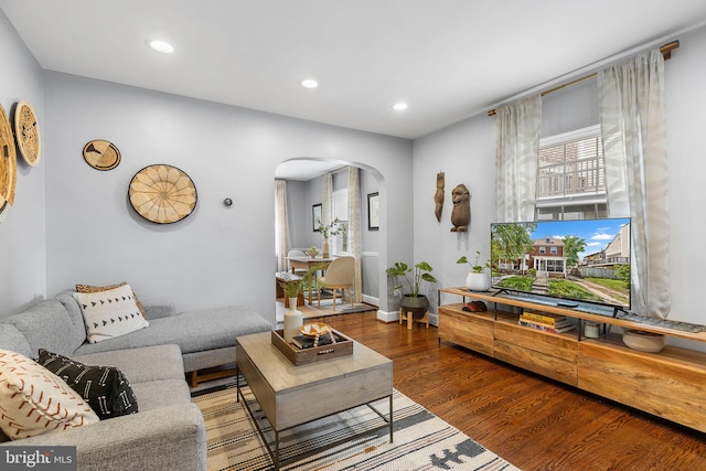 living area with arched walkways, wood finished floors, recessed lighting, and baseboards