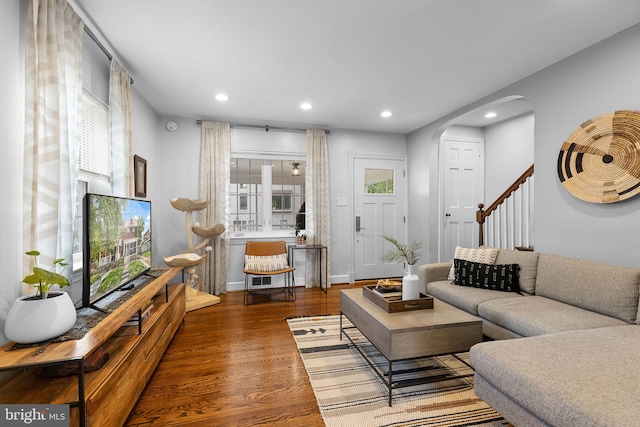 living room with recessed lighting, wood finished floors, arched walkways, and stairway