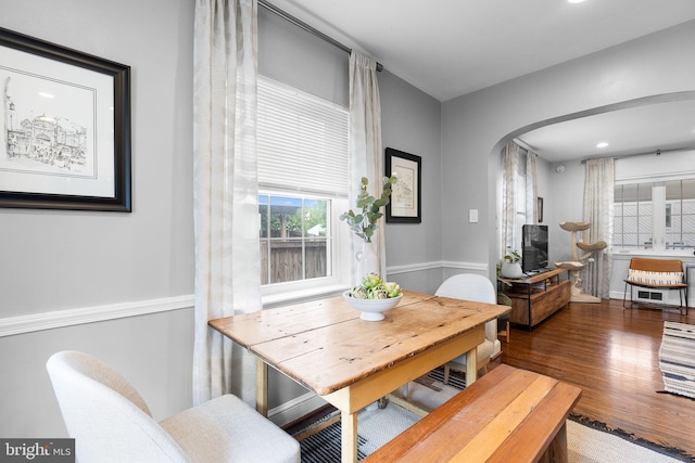 dining room featuring arched walkways and wood finished floors
