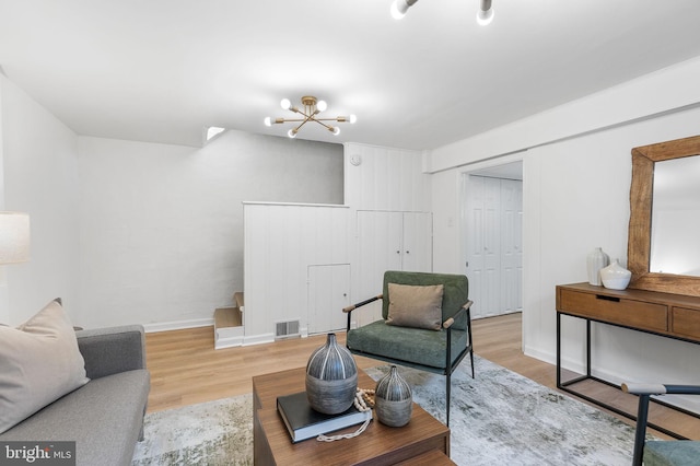 living room featuring wood finished floors, a chandelier, and baseboards