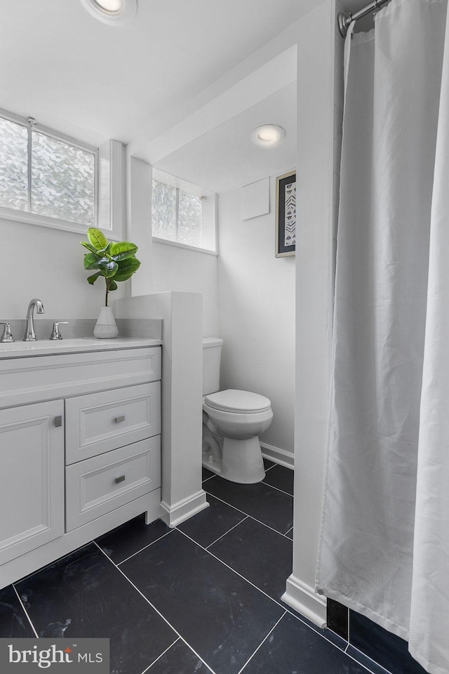bathroom with toilet, vanity, tile patterned floors, and a shower with curtain