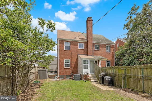 rear view of house with entry steps, brick siding, a chimney, central air condition unit, and roof with shingles