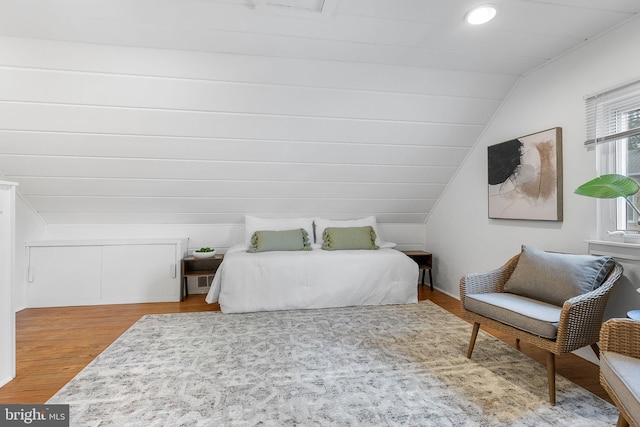 bedroom with wood finished floors and lofted ceiling
