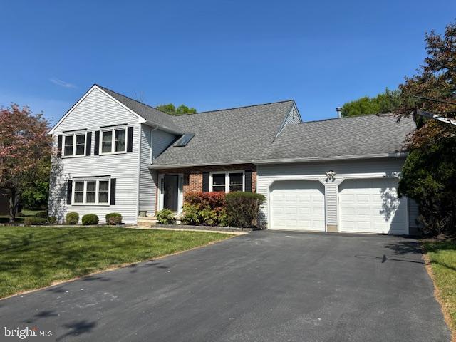 view of front of house featuring a front yard, roof with shingles, aphalt driveway, and an attached garage