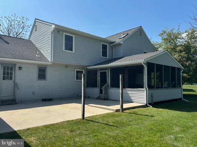 back of property with roof with shingles, a sunroom, a patio area, and a lawn