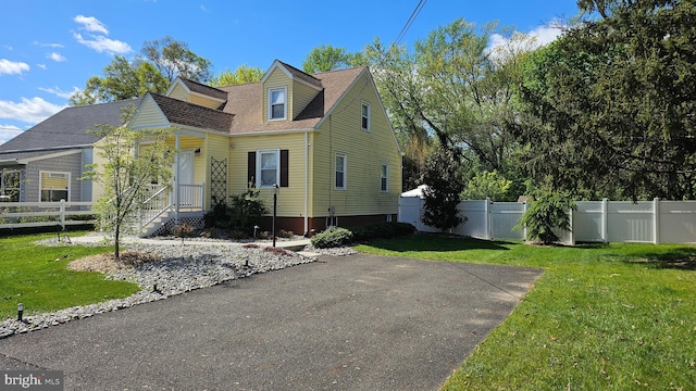 cape cod home featuring fence and a front yard