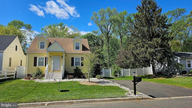 cape cod-style house with fence and a front lawn