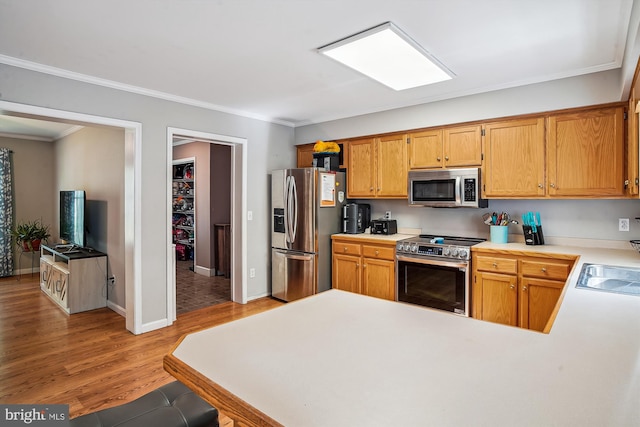 813 Petinot Pl, Stevensville, MD 21666 - kitchen featuring appliances with stainless steel finishes, crown molding, light countertops, a peninsula, and light wood-type flooring