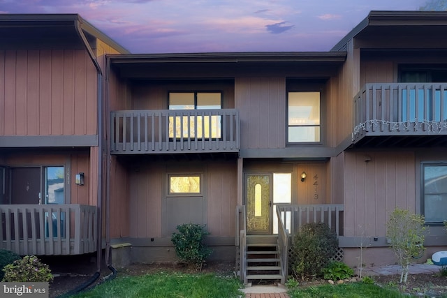 back of house at dusk featuring a balcony